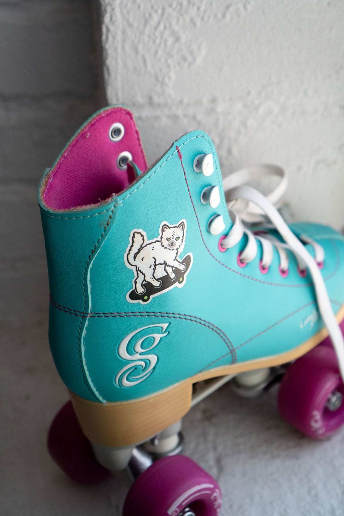 Reflective sticker of a cute cat on a skateboard shown stuck to a child's rollerskate