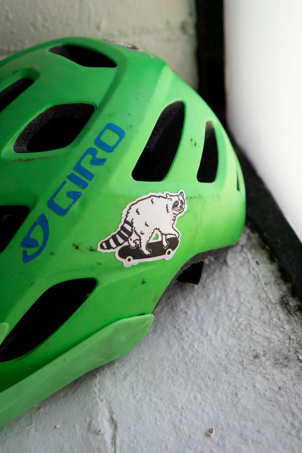 Reflective sticker of a cute raccoon on a skateboard shown on a kids bike helmet