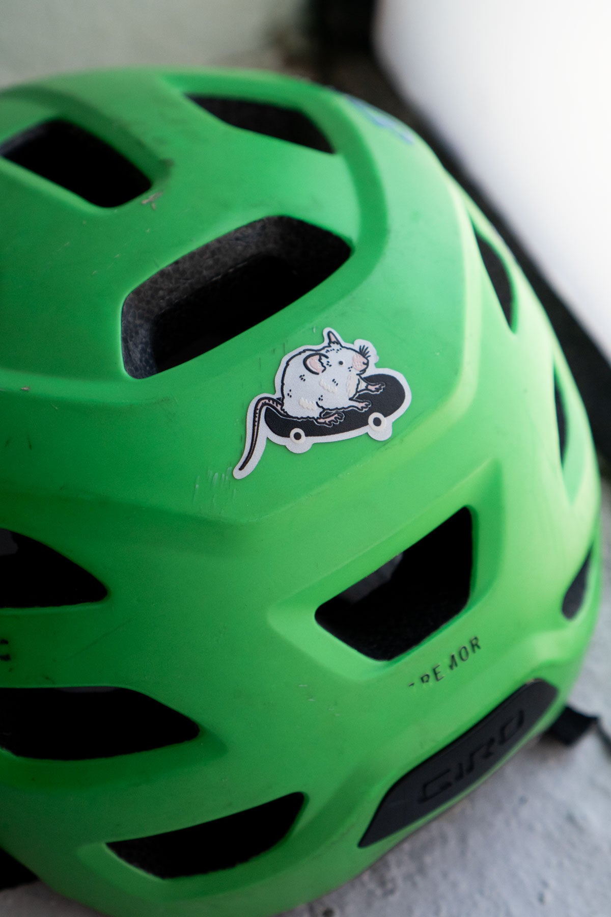 Reflective sticker of a cute rat on a skateboard shown on a child's bike helmet