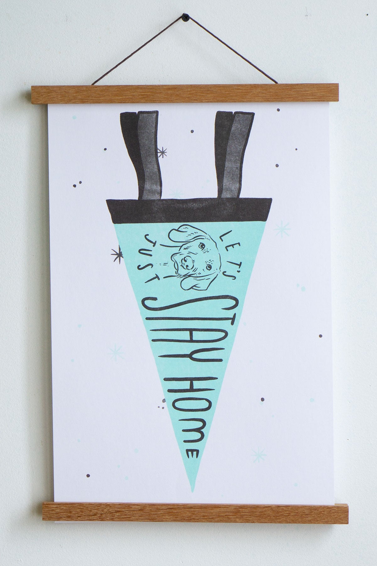 print of light blue pennant on white background with black trim and drawing of dog with the words let's just stay home inside