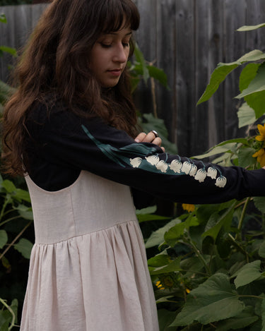 Woman wearing a black long-sleeved tee with white floral patterns in a garden setting