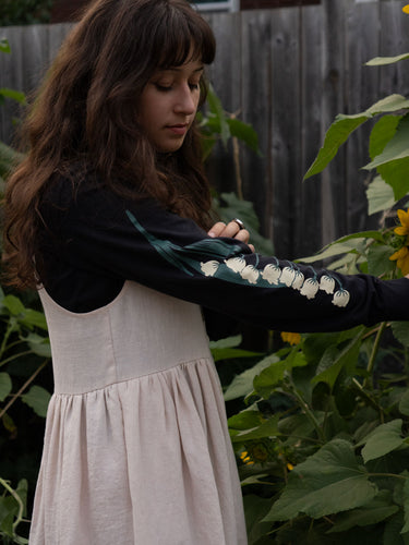 Woman wearing a black long-sleeved tee with white floral patterns in a garden setting