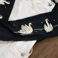 Close-up of a black long-sleeved tee with white swan designs 
