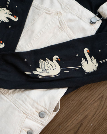 Close-up of a black long-sleeved tee with white swan designs 