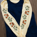 Butter yellow long-sleeved t-shirt with orangey red and green poppy floral pattern layered under a denim pinafore dress
