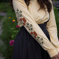 Person wearing a butter yellow long-sleeve shirt with floral sleeve prints, standing outdoors.