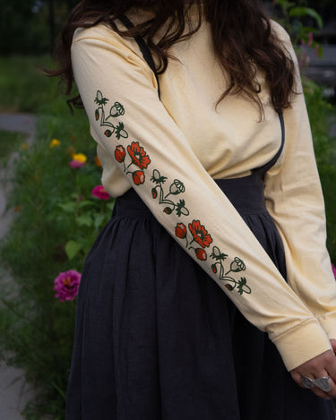 Person wearing a butter yellow long-sleeve shirt with floral sleeve prints, standing outdoors.