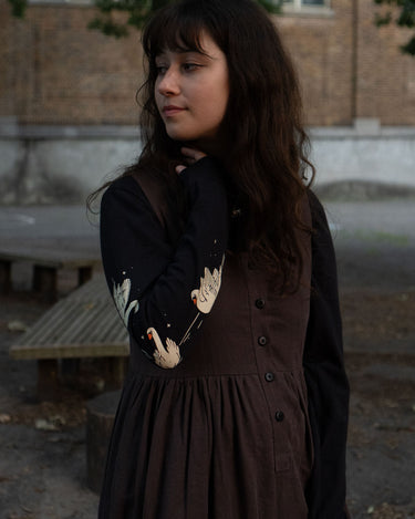 Woman wearing a dark dress with a patterned long-sleeve tee in an outdoor setting