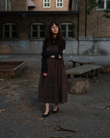 Woman standing in an urban setting with a brick building in the background