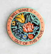 Round magnet with central floral design encircled by the words "I will make it out of this alive"