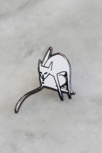 lapel pin of white cat licking itself with leg up and a long tail