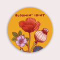 circular sticker of pink and red flowers on yellow background with the words "Bloomin Idiot" 