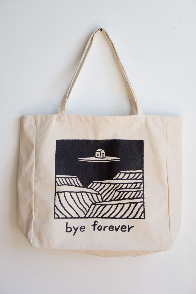 natural canvas tote bag with square image in black of house floating on island with text reading "Bye forever" below illustration