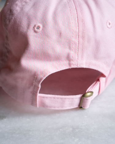 closeup of back of pale pink baseball cap with brass clasp 