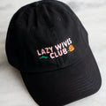 black baseball cap with pale pink embroidery text saying lazy wives club with red rose with green stem behind text